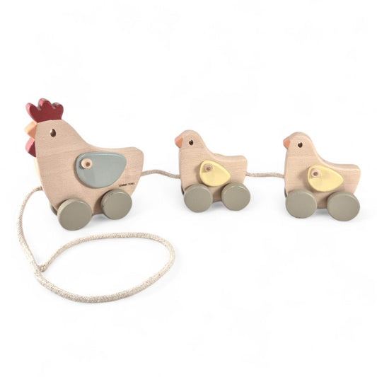 Mama chicken and her two chicks wobble along on the Timmy Toys Chicken Family Pull-Along Baby Wooden Toy, crafted from natural materials and painted with non-toxic colors, perfect for toddlers to develop motor skills and engage in imaginative farmyard play.