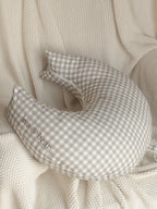 Ava & Bear Ash Brown Gingham Crescent Nursing Cushion elegantly curves around the body, offering optimal support for mother and baby with its 100% cotton twill fabric, eco-friendly design, and convenient loop handle for easy portability.