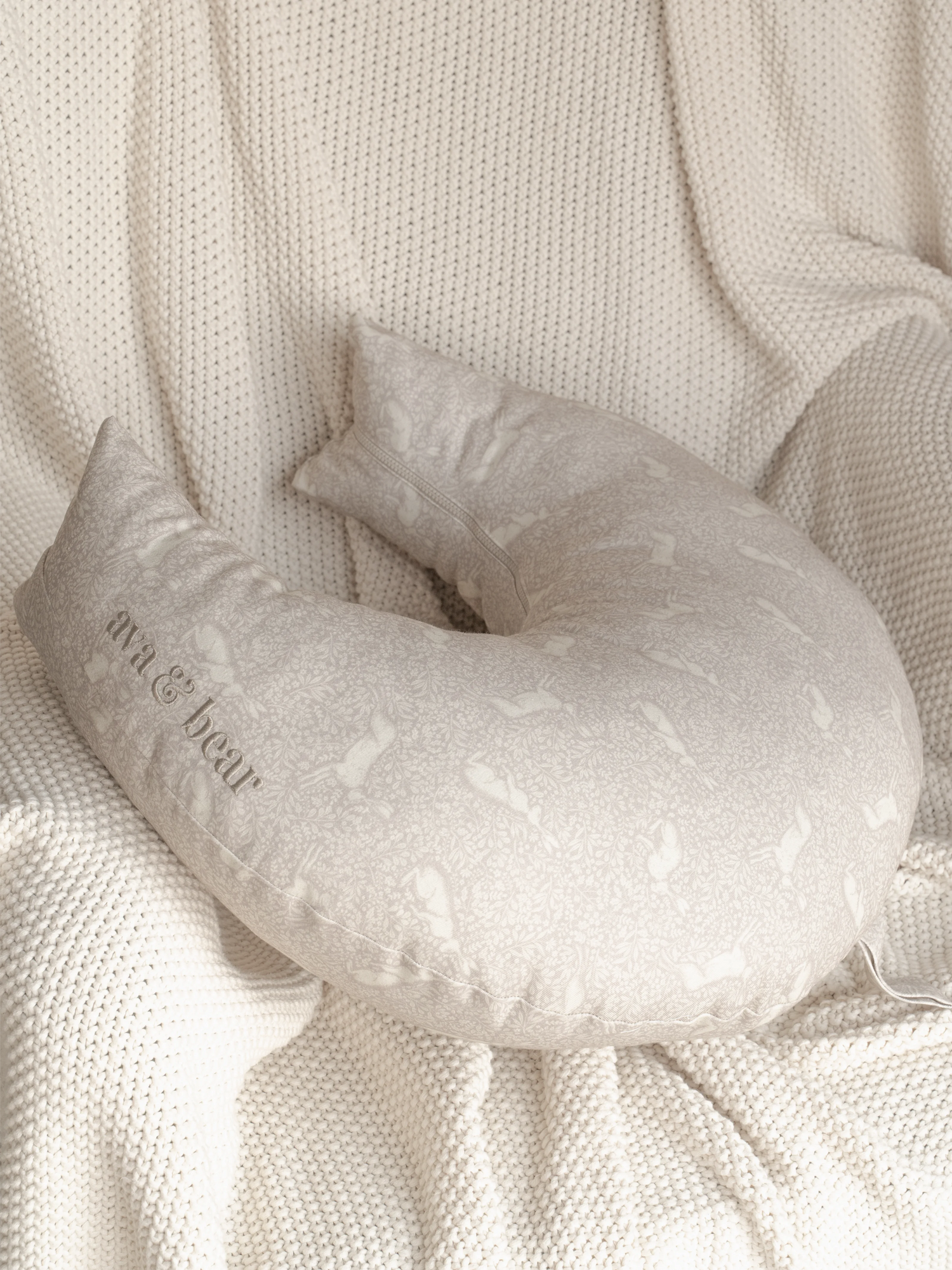 Crescent-shaped Ava & Bear Meadow Rabbit Nursing Cushion, crafted from 100% cotton twill, offers optimal support for mom and baby with its eco-friendly design and convenient carry handle, perfect for on-the-go comfort.